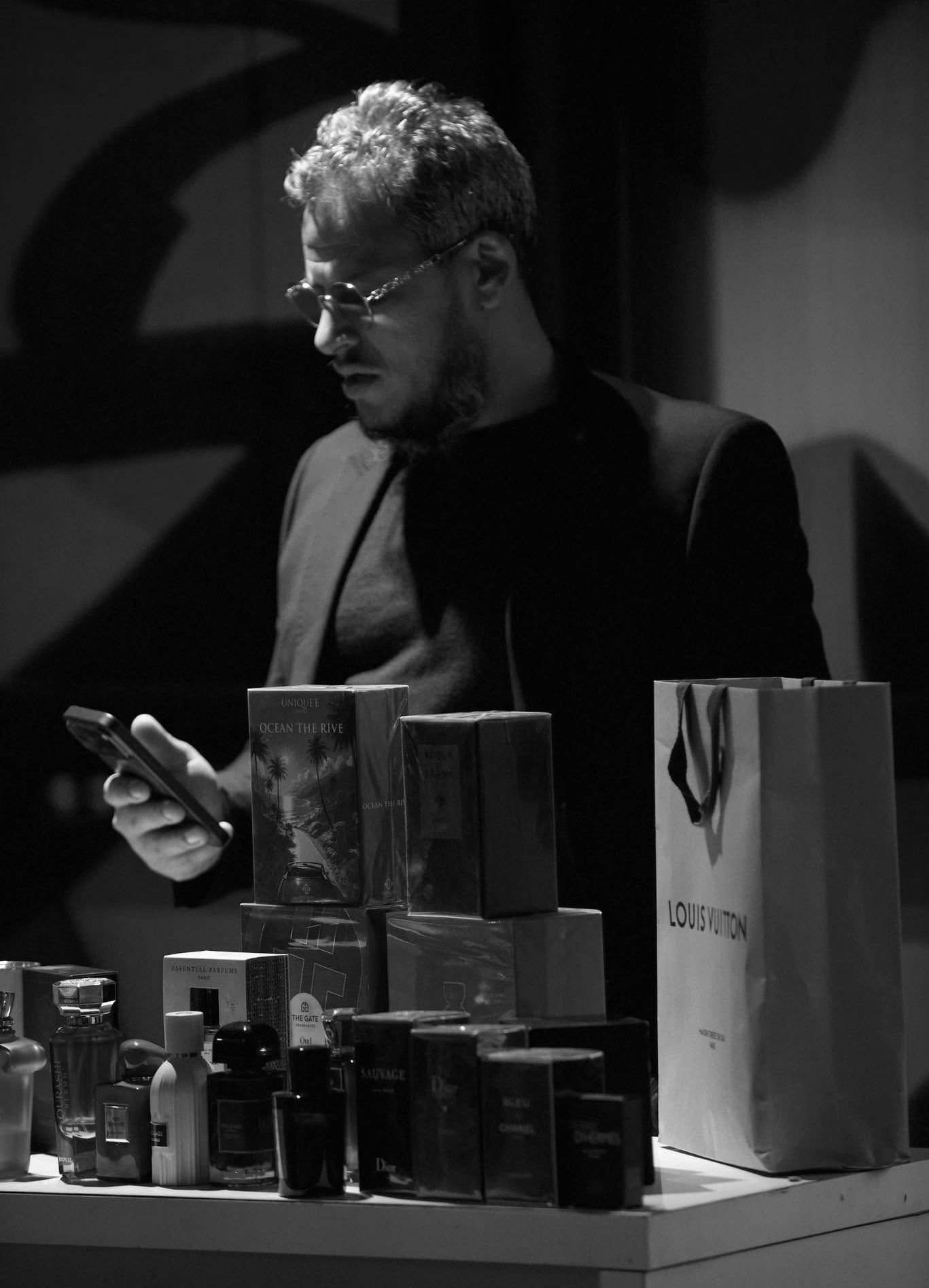 Le fondateur de Bisso Fragrance derrière son comptoir, entouré de flacons et de coffrets de parfums